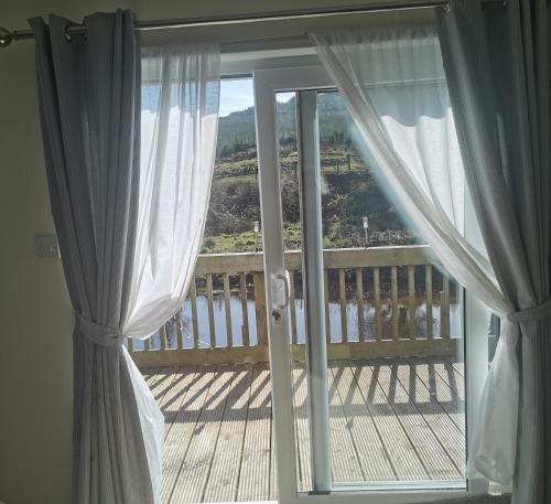 a view of a balcony from a window with curtains at Homeston Lodge in Drumlemble