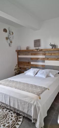 una camera da letto con un grande letto bianco con testiera in legno di bambôô a Les Avirons