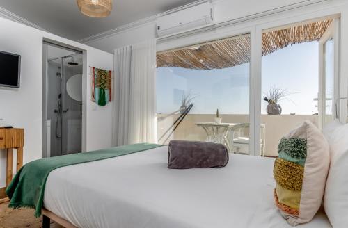 Un dormitorio con una cama blanca y una ventana grande. en Villa Center - Alojamento Local, en Grândola