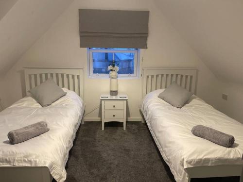 2 camas individuales en una habitación con ventana en Hyfrydol Bach, en Maesteg