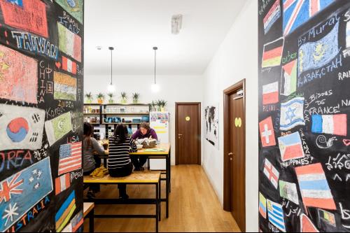 a room filled with tables and chairs and a poster on the wall at Avenue Hostel in Budapest