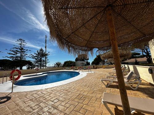 een parasol en stoelen naast een zwembad bij PREMIUM - Dúplex Lujo Recién Reformado con Jardín, Piscina, Parking, Aire Acondicionado - Los Caños de Meca - 50m playa in Los Caños de Meca