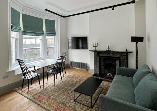 Regents Park Apartments في لندن: غرفة معيشة مع أريكة خضراء وطاولة