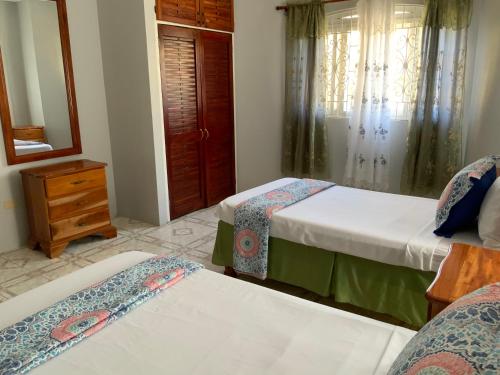a bedroom with two beds and a mirror at Poinciana House in Montego Bay