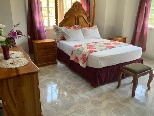 a bedroom with a bed and a table and a chair at Poinciana House in Montego Bay