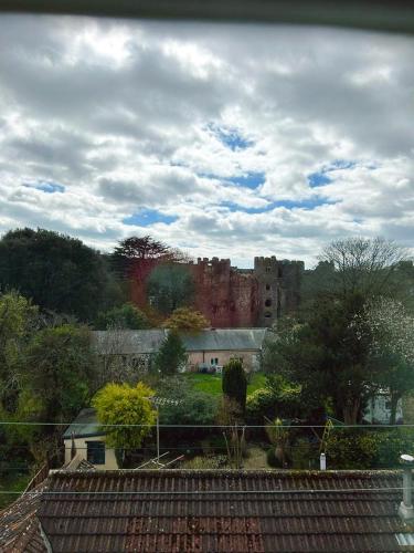 a castle in the middle of a field with trees at Dylan Thomas Sea View in Laugharne