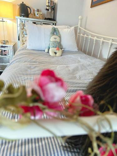 a bed with pink roses and a stuffed animal on it at Dylan Thomas Sea View in Laugharne