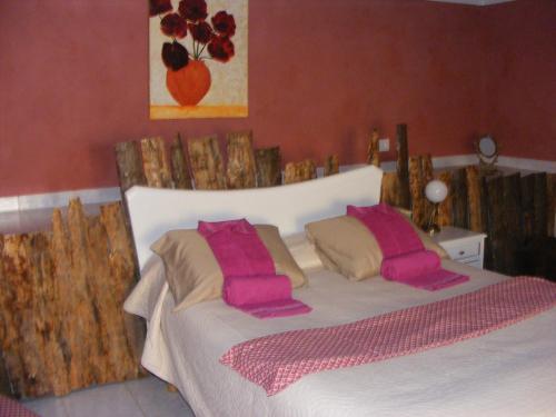 a bedroom with a white bed with pink pillows at Casa Thocamalu's in Covelo