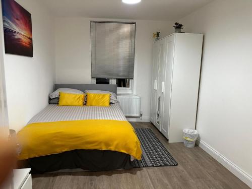 ein Schlafzimmer mit einem Bett mit gelber Bettwäsche und einem Fenster in der Unterkunft 2 bedroom apartment in London