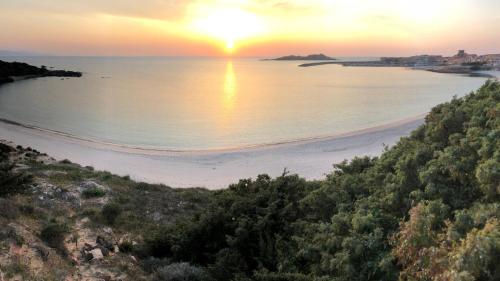a beach with the sun setting over the water at Miramare Isola Rossa in Isola Rossa