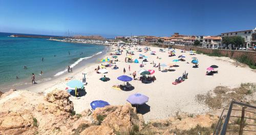 a beach with many people with umbrellas and the ocean at Miramare Isola Rossa in Isola Rossa