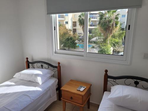two beds in a room with a window and a table at ELeAN VILLA in Paphos City