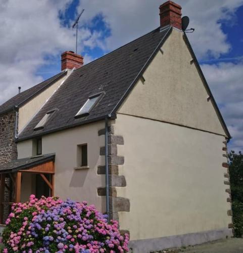 Une maison blanche avec un bouquet de fleurs devant elle dans l'établissement Gîte la Mer, à la campagne en Normandie, proche du Mont St Michel, à Lolif