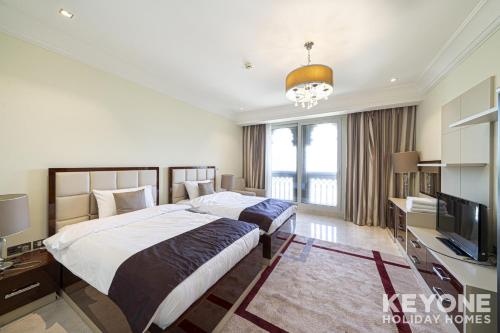 twee bedden in een hotelkamer met een televisie bij Two Bedroom Sea View Apt with Private Beach Access in Dubai