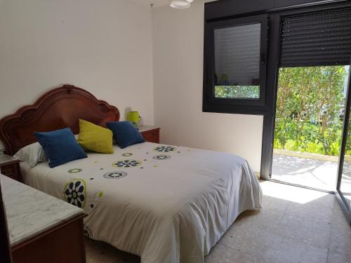 1 dormitorio con 1 cama con almohadas azules y amarillas en JARDIN, TERRAZA Y BARBACOA, en O Grove
