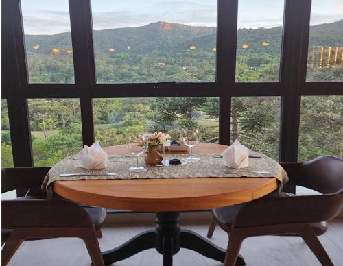 a table with wine glasses and a view of the mountains at Mirante da Colyna Hotel & SPA in Monte Verde