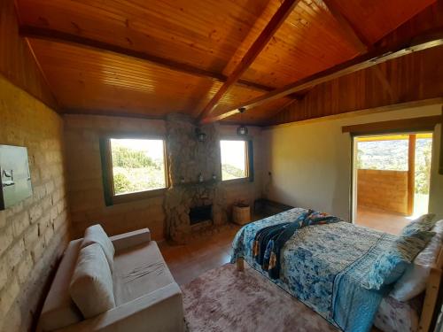 a bedroom with a bed and a couch in a room at Cabana do Camelo in São Bento do Sapucaí