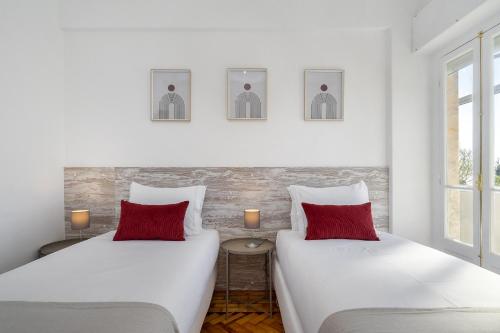 2 łóżka z czerwonymi poduszkami w pokoju w obiekcie WHome Peaceful River Views in Algés perfect for Families w mieście Algés
