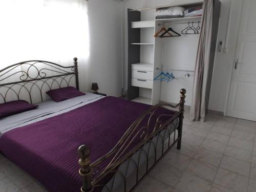 1 dormitorio con cama con sábanas moradas y armario en Aux portes de la Soufrière, Baillif en Baillif