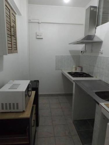 a white kitchen with a stove and a microwave at Aux portes de la Soufrière, Baillif in Baillif