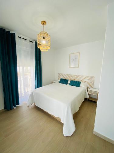 Habitación blanca con cama blanca y lámpara de araña. en Arunda Home, en Ronda