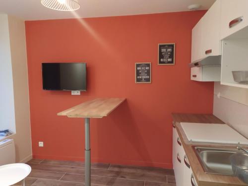 Il comprend une cuisine avec des murs orange et une télévision murale. dans l'établissement Résidence du Panthéon, à Le Mont-Dore