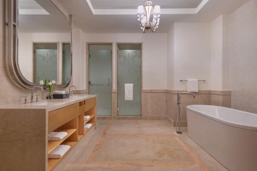 a bathroom with a tub and a large mirror at The St. Regis Doha in Doha