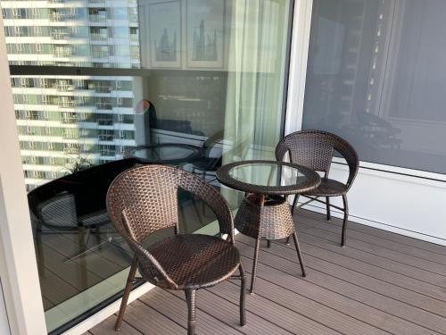 3 Stühle und ein Glastisch auf dem Balkon in der Unterkunft Panorama City apartment 2 rooms 19th floor, free parking in Bratislava