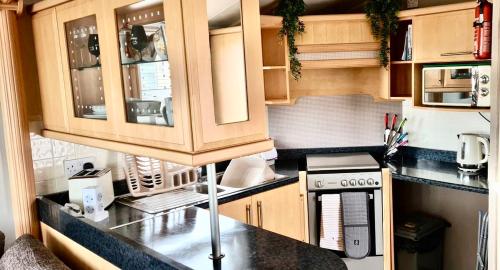 a kitchen with wooden cabinets and a counter top at Wrights Retreat 4 Lunan View St Cyrus Caravan Park in Saint Cyrus