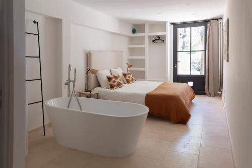 a white bath tub in a bedroom with a bed at Domaine de la Xavolière in Saint-Cézaire-sur-Siagne
