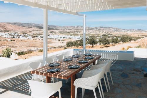 a wooden table and chairs on a balcony with a view at Ventu Paros Villa - Pet Friendly in Márpissa