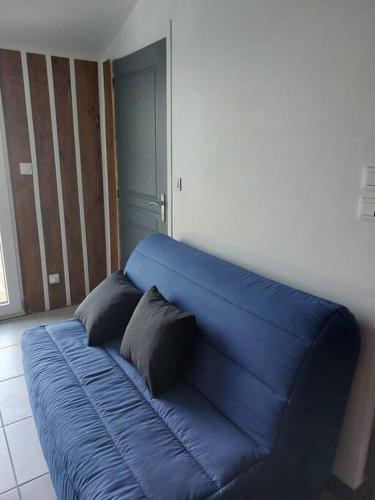 um sofá azul num quarto com duas almofadas em Studio 4 personnes em Montagne