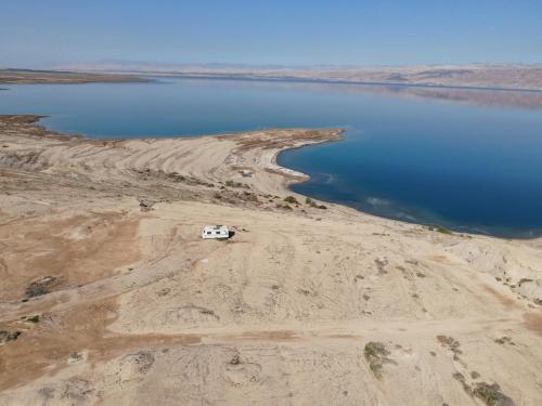 un camper parcheggiato sul lato di un corpo d'acqua di שלווה בים - צימר ים המלח, deadsea a Ovnat