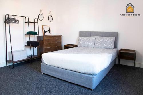 a bedroom with a bed and a dresser and a bed sidx sidx at Spacious 3 bed Terrace House with free parking & free Wi-Fi by Amazing Spaces Relocations Ltd in Saint Helens