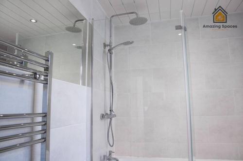 a shower with a glass door in a bathroom at Spacious 3 bed Terrace House with free parking & free Wi-Fi by Amazing Spaces Relocations Ltd in Saint Helens