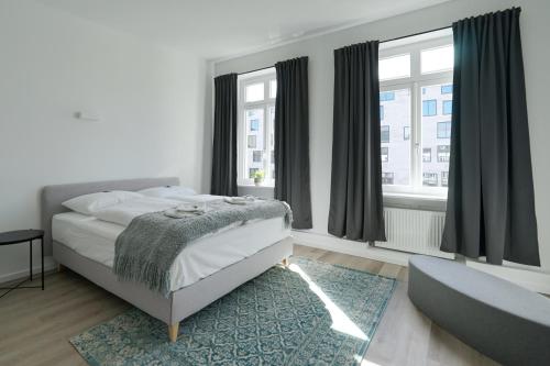 1 dormitorio con cama, sofá y ventanas en vonBehling Boutique Apartment - Gemeinsam leben am Puls der Innenstadt en Wiesbaden