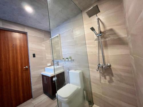 a bathroom with a shower and a toilet and a sink at Cozy Spacious Hotel Type Condo with PS5 Smart TV and WiFi in Manila