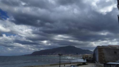 a beach with a cloudy sky and the ocean at L'amuri du mare in Trapani