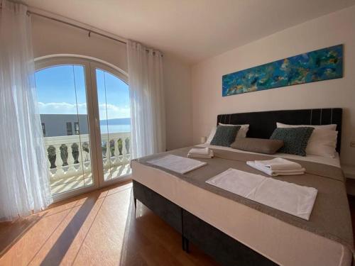 a bedroom with a large bed and a large window at Villa Mihaela - Apartment Ika in Cesarica