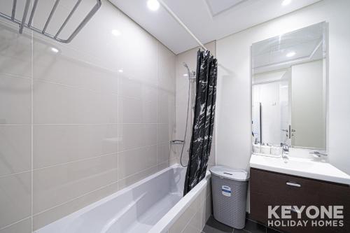 a bathroom with a tub and a sink and a mirror at Modish Studio in Damac Hills 2 in Dubai