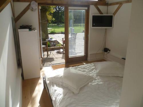 una camera con un letto in una stanza con una finestra di Oak Frame Barn Studio in Rural AONB Chiddingfold a Chiddingfold