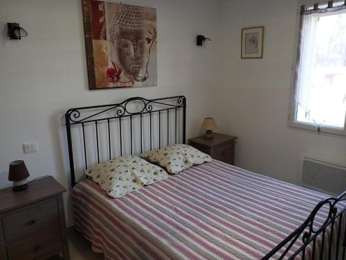 ein Schlafzimmer mit einem Bett mit einer gestreiften Decke und einem Fenster in der Unterkunft Le refuge de Sissou in Pontevès