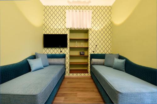 - deux canapés bleus dans une chambre avec une télévision dans l'établissement La Casa di Vittoria Sorrento, à Sorrente