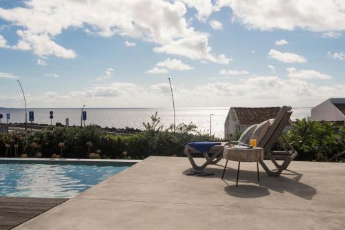 a chair and a table next to a swimming pool at Green&Houses in Ponta Delgada