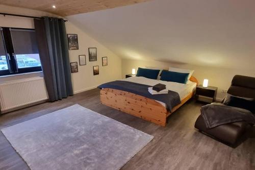 a bedroom with a large bed and a chair at Capa Ferienwohnung Pfalz in Neustadt an der Weinstraße