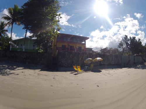 a house on the beach with two umbrellas in the sand at Pousada Casa na Praia in Ubatuba
