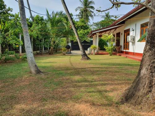 a house with two trees in front of a yard at Villa 87 in Katunayake