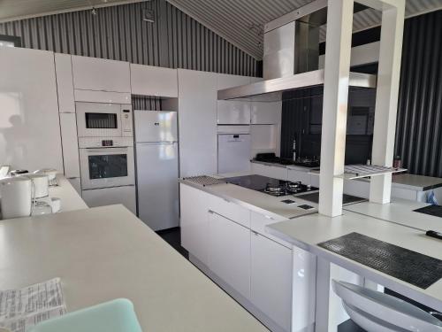 eine weiße Küche mit weißen Schränken und Geräten in der Unterkunft LES CERISIERS 2 in Nogaro