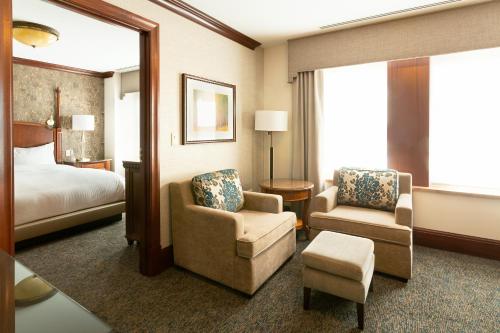 um quarto de hotel com uma cama e duas cadeiras em The Towers at The Kahler Grand em Rochester