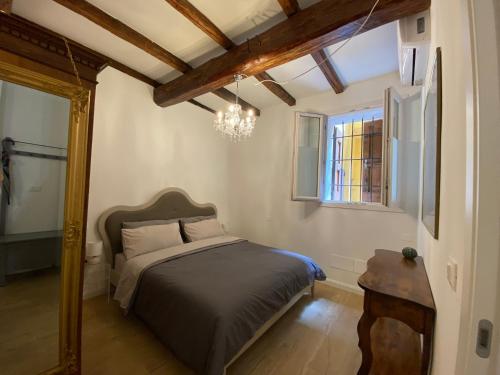 a bedroom with a bed and a window and a chandelier at Il cortile tra i portici in Bologna